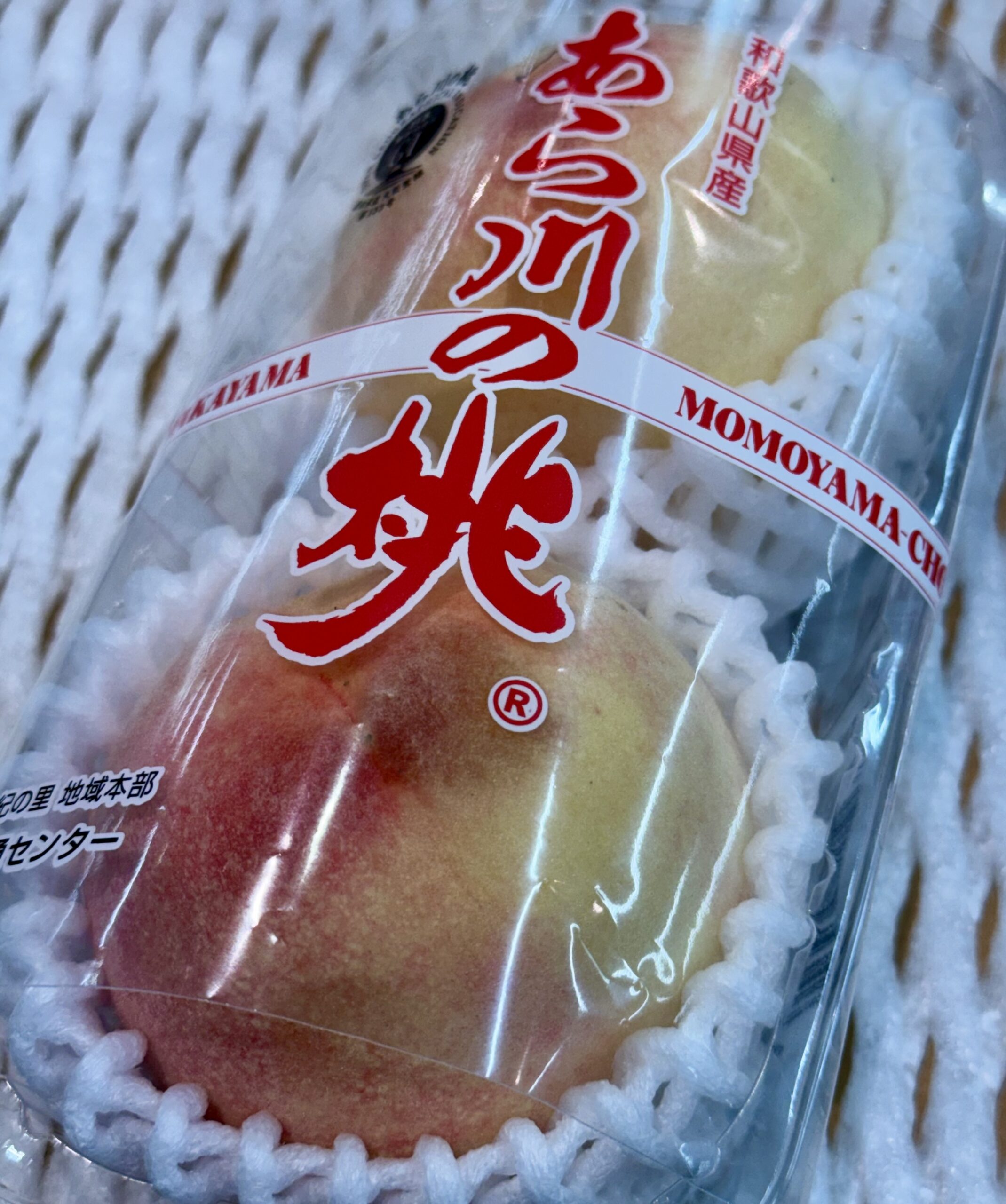 スーパーで見つけた、和歌山県産あら川の桃。GIマークの帯が目印